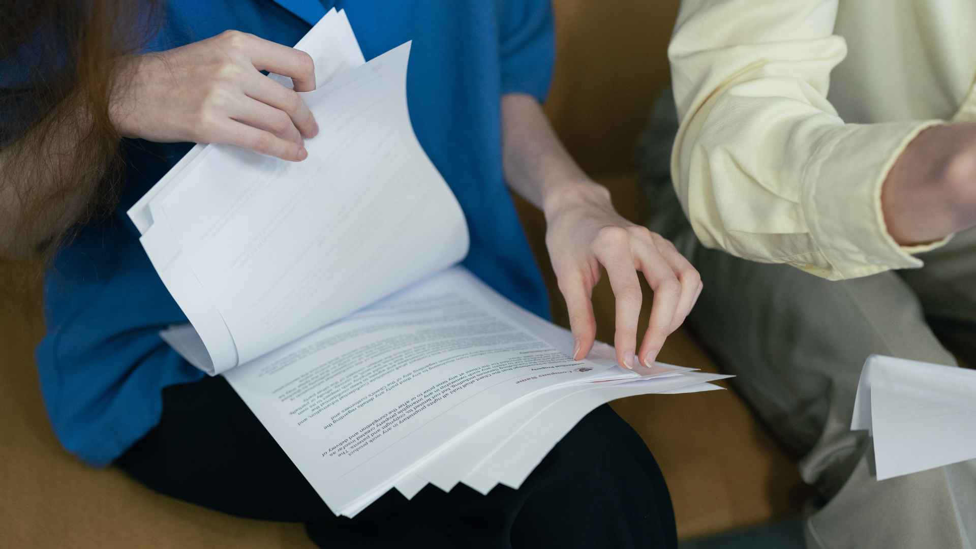 Close-up of two people sitting together reviewing a stack of printed documents